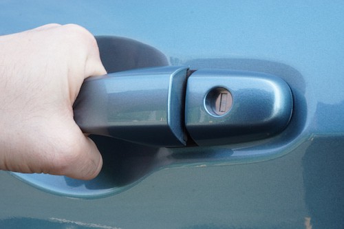 person pulling car door handle because they are locked out of the car